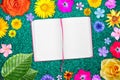 Beautiful flower frame with notebook in center on light blue particle board background. Floral composition of spring or summer flo Royalty Free Stock Photo