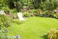 A beautiful flower garden with yellow deck chair on a green lawn Royalty Free Stock Photo