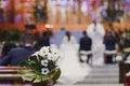 Beautiful flower wedding decoration in a church. Selective focus. Unrecognizable blurred Groom and bride on background. Marriage Royalty Free Stock Photo