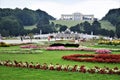 Beautiful flowerbeds in the garden of Schonbrunn Palace in Vienna, a large fountain and an airplane building in the background.