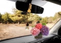 Beautiful flowers and air freshener hanging on view mirror in car
