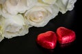 Beautiful flowers on black background with cream roses bouquet and chocolates red heart shaped Royalty Free Stock Photo