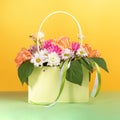 Beautiful flowers bouquet in gift light green paper bag with ribbons on yellow-green background Royalty Free Stock Photo