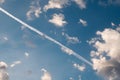 Beautiful fluffy cloudscape in the morning with white contrail trail of the plane flying in the sky.