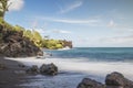 Beautiful foamy ocean waves crashing on the rocky shore under a blue summer Royalty Free Stock Photo