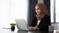 A beautiful and focused millennial Asian Muslim businesswoman is working on her laptop at her desk Royalty Free Stock Photo