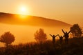 Beautiful fog in the morning. Silhouettes of three people - dad and two children against a beautiful golden sunrise. Hills in the Royalty Free Stock Photo