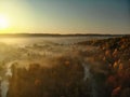 Beautiful foggy forest scene in autumn with orange and yellow foliage. Aerial early morning view of trees and river Royalty Free Stock Photo