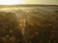 Beautiful foggy forest scene in autumn with orange and yellow foliage. Aerial early morning view of trees and river Royalty Free Stock Photo