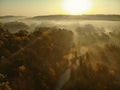 Beautiful foggy forest scene in autumn with orange and yellow foliage. Aerial early morning view of trees and river Royalty Free Stock Photo
