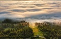 Foggy sunrise in mountains. Sea of fog behind top of the hill Royalty Free Stock Photo