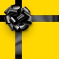 Beautiful foil black bow with ribbon on yellow background