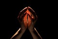 Beautiful folded hands with light on top, black background. Prayer or creating a miracle. Royalty Free Stock Photo
