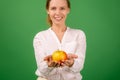 A beautiful forty-year-old woman holds a fresh apple in her hands on a green background. Healthy eating, vegetarianism, healthy Royalty Free Stock Photo