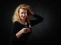 Beautiful forty years blonde in black evening dress with snifter of brandy