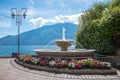 Beautiful fountain at lake shore Gardasee, tourist resort Limone with colorful impatiens flowers