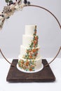 Beautiful four tiered wedding cake decorated with colorful icing flowers, surrounded by metal ring and bouquet Royalty Free Stock Photo