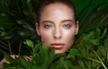 Beautiful fresh girl with perfect skin, natural make-up and green leaves. Beauty face. Royalty Free Stock Photo