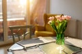 Beautiful fresh pink tulips bouquet in green glass vase on table in warm sunset sun lights against balcony window in Royalty Free Stock Photo