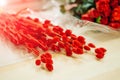 Beautiful fresh red flowers lying on the light wooden table near the red roses Royalty Free Stock Photo