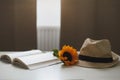 Beautiful fresh sunflower, straw hat and a book. Interior decoration. Summer concept. Flower card. Summer vacation time. Flat lay