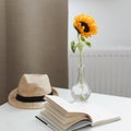 Beautiful fresh sunflower, straw hat and a book. Interior decoration. Summer concept. Flower card. Summer vacation time. Flat lay