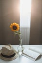 Beautiful fresh sunflower, straw hat and a book. Interior decoration. Summer concept. Flower card. Summer vacation time. Flat lay