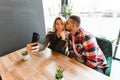 Beautiful Friends Taking Photos In Cafe. Happy young couple is doing selfie, smiling and sitting at the cafe, rest concept Royalty Free Stock Photo