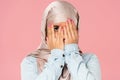 Frightened muslim girl in hijab closing face, isolated on pink