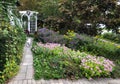 Beautiful Front Garden with Blooming Pink Sedums, Brick Pathway and White Arbor Royalty Free Stock Photo