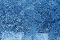 Beautiful frost and ice pattern on window surface in navy blue.