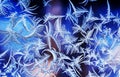 Beautiful frosty pattern with various ornate patterns on the transparent glass on the winter window in delicate lilac and blue