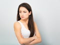 Beautiful frowning angry business woman in white shirt with hand under the face and looking serious on blue background. Closeup