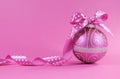 Beautiful fuchsia pink festive bauble ornament with polka dot ribbon on a feminine pink background with copy space