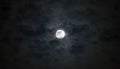 Beautiful full moon beneath wispy blue gray moody clouds, dramatic night sky