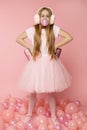 Beautiful fun girl in fashion clothes on a pink background with pink balloons and accessories with pout pink bubble in lips.