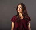 Beautiful fun humor grimacing angry woman with long brown curly healthy hair style looking up in red shirt. Closeup studio