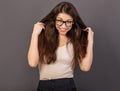 Beautiful fun humor toothy laughing smiling business woman in glasses holding the hands long brown hair in white shirt on grey