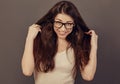 Beautiful fun humor toothy laughing smiling business woman in glasses holding the hands long brown hair in white shirt on grey