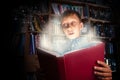 Beautiful funny child holding a big book with magical light looking amazed Royalty Free Stock Photo