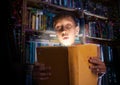 Beautiful funny child holding a big book with magical light looking amazed