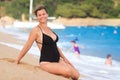 Beautiful funny girl in black swimsuit on sandy beach in Lloret de Mar