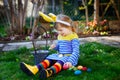 Beautiful funny little toddler girl with bunny ears having fun with traditional Easter eggs hunt on warm sunny day Royalty Free Stock Photo