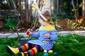 Beautiful funny little toddler girl with bunny ears having fun with traditional Easter eggs hunt on warm sunny day Royalty Free Stock Photo