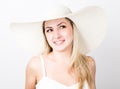 Beautiful funny young blonde woman in white tank top and a large white hat smiling Royalty Free Stock Photo