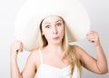 Beautiful funny young blonde woman in white tank top and a large white hat smiling and poses faces Royalty Free Stock Photo