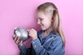 Beautiful funny young girl with silver piggy bank on pink background. save money concept. Royalty Free Stock Photo