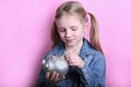 Beautiful funny young girl with silver piggy bank on pink background. save money concept. Royalty Free Stock Photo