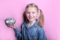 Beautiful funny young girl with silver piggy bank on pink background. save money concept. Royalty Free Stock Photo