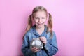 Beautiful funny young girl with silver piggy bank on pink background. save money concept. Royalty Free Stock Photo